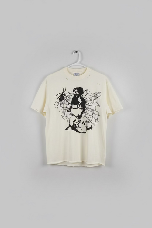 An off-white distressed t-shirt hanging on a hanger, featuring a black graphic print of a woman with a sword surrounded by a spider and web, next to a white t-shirt.